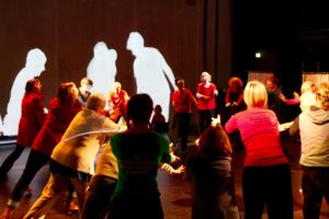 Group of people dancing with projected silhouettes in the background