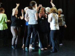 Group of older adults smiling and dancing in a studio setting.