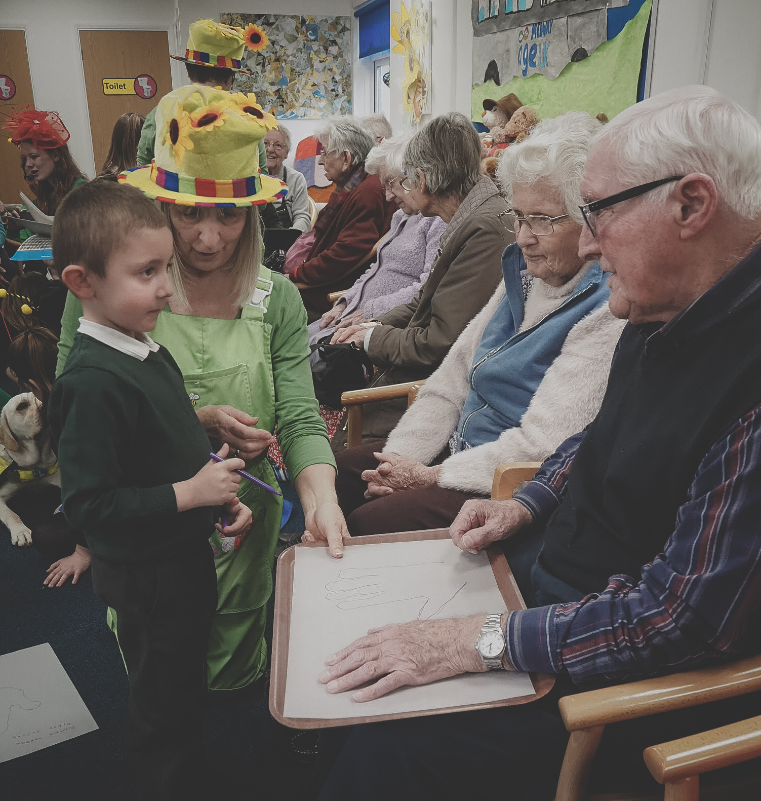 A school child talks to old people in an old people's home.