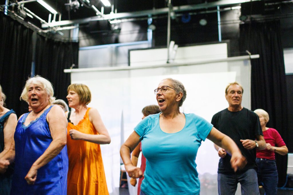 A group of people dance in coloured clothes.