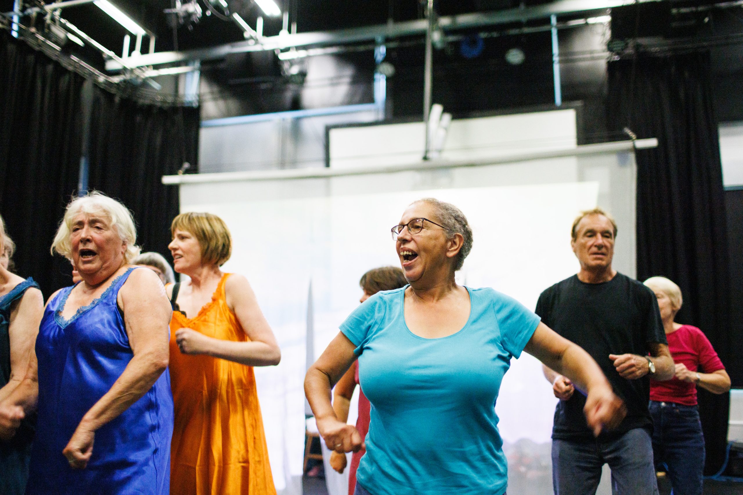 A group of people dance in coloured clothes.