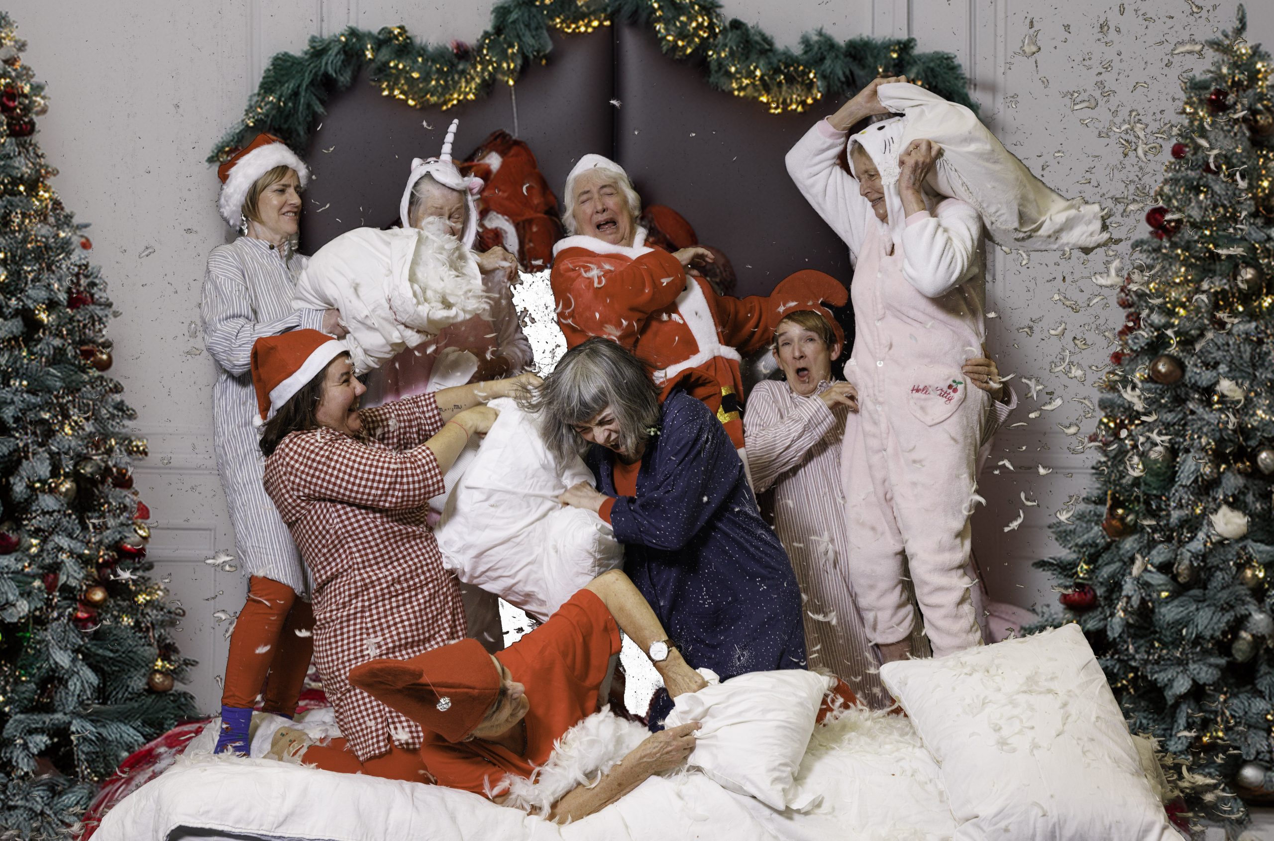 7 women dressed in Christmas pyjamas have a pillow fight