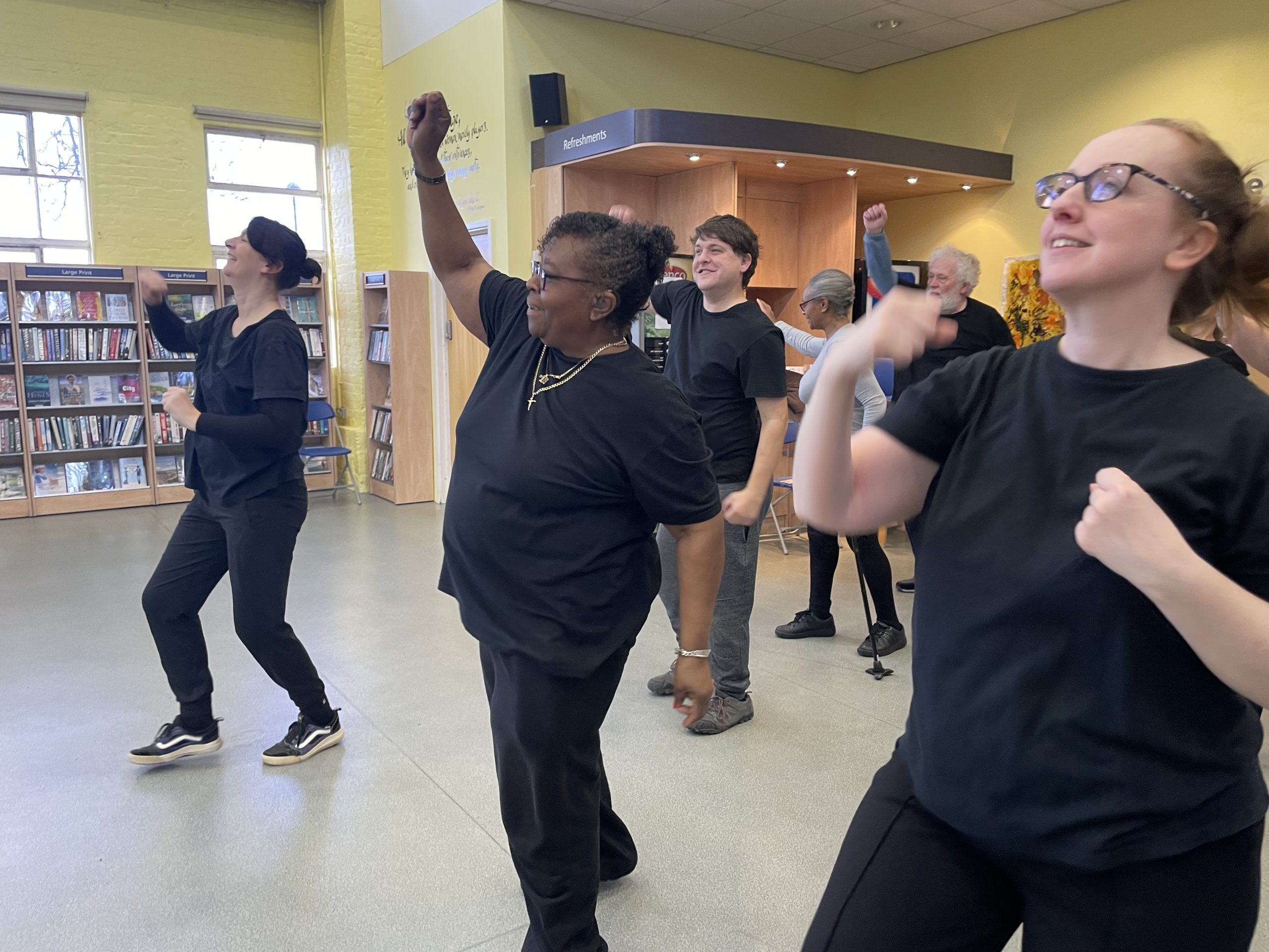 A group of people dressed in black dance in a library.