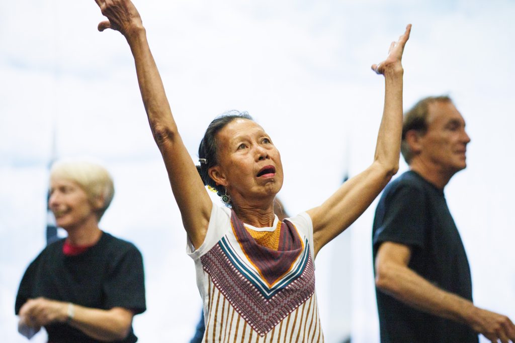 A lady stands with arms outstretched, looking up to the sky.