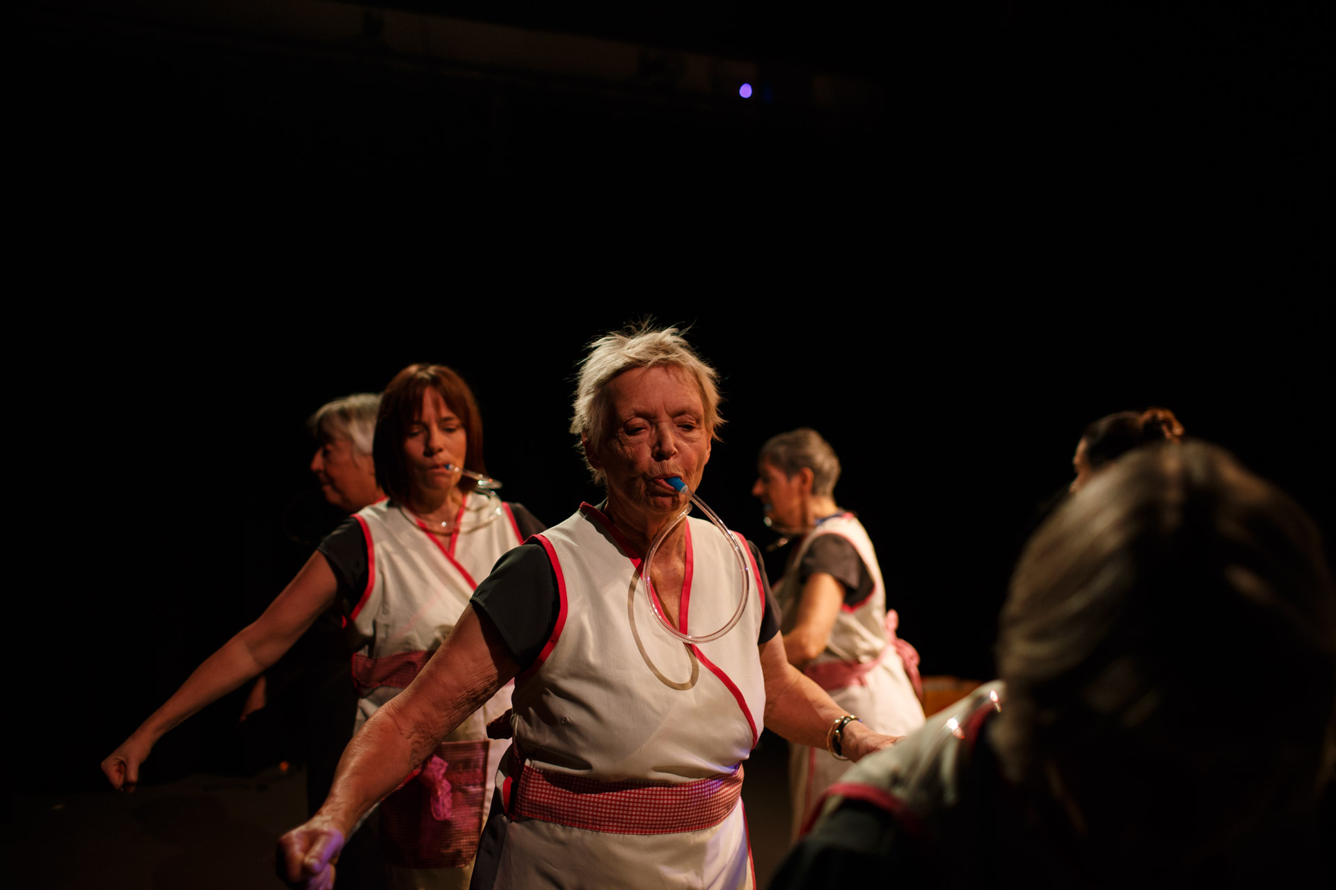 Women drinking water through tubes and wearing white tabards walk round in a circle.