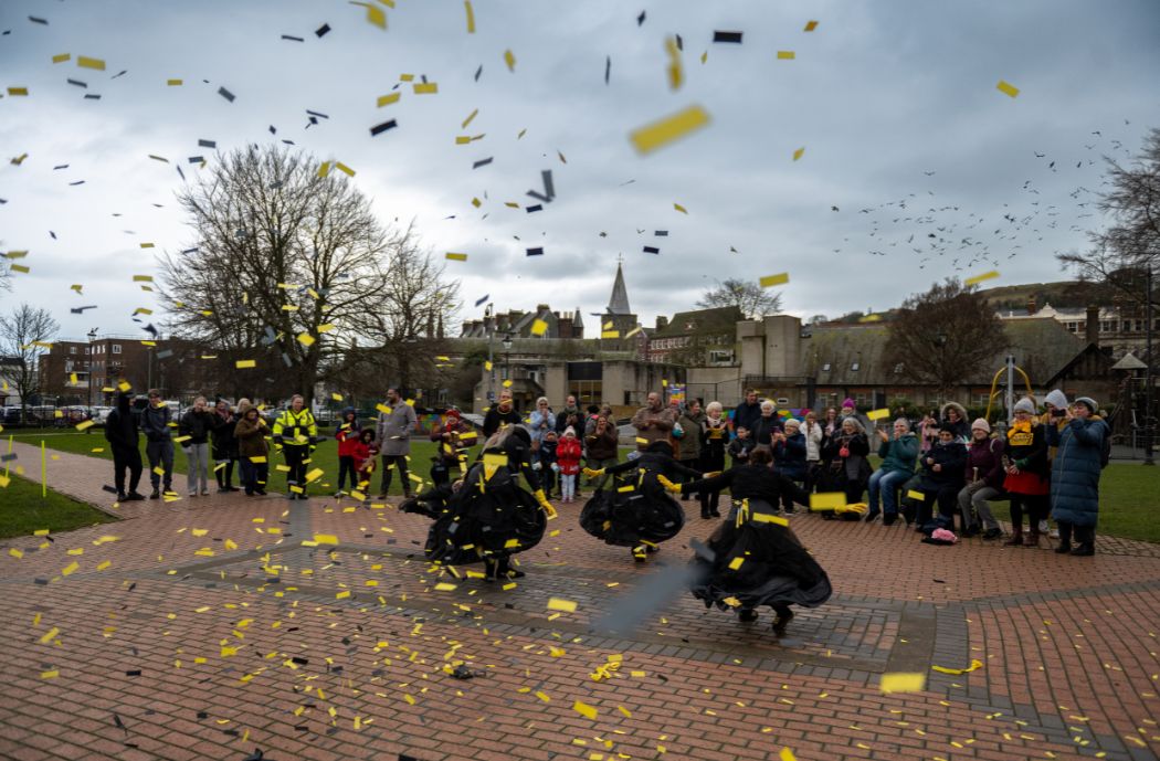 Moving Memory perform Cracking the Crinoline at Dover Winter Light Up in Pencester Gardens, Dover. Yellow confetti flies around.