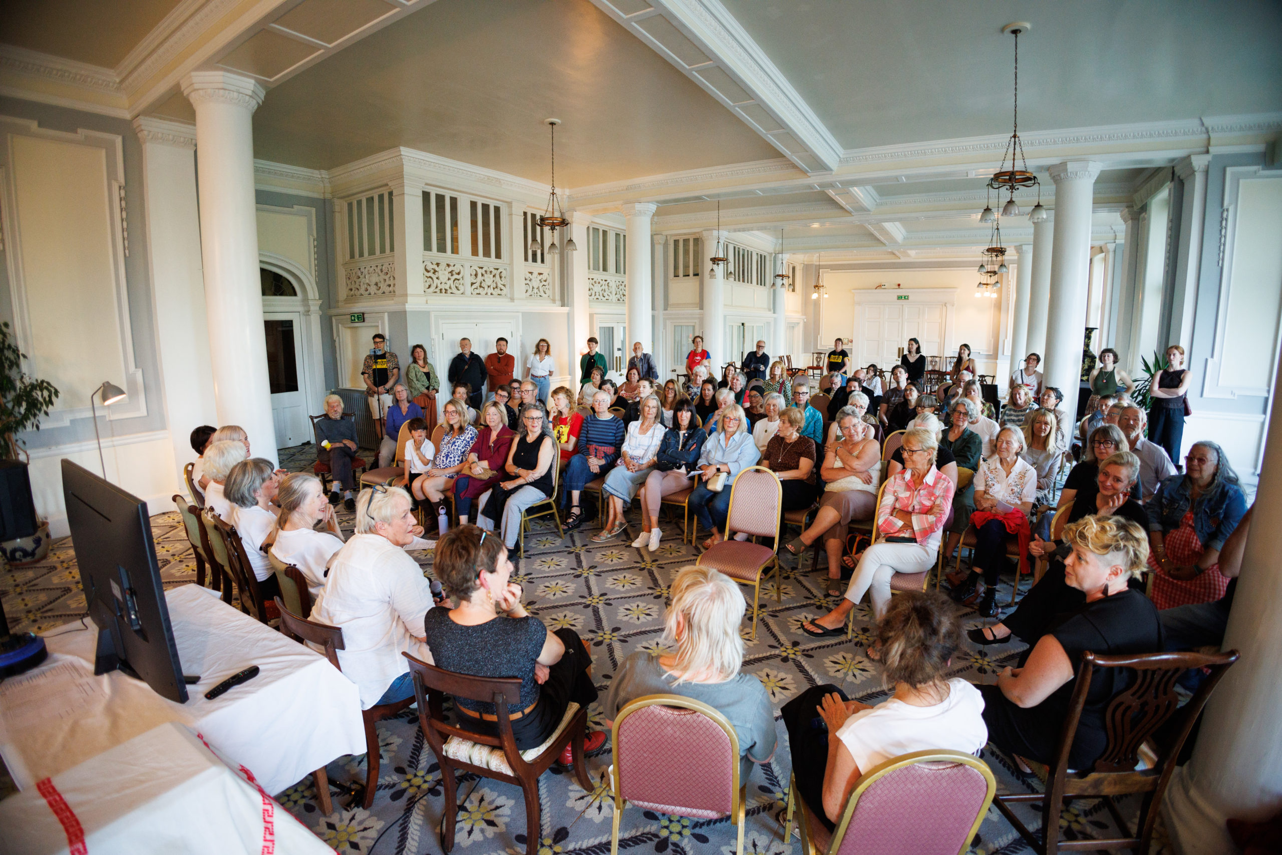 Audience seated in a wide circle during the Moving Memory event "We'll Take It From Here Dear" in the grand ballroom.