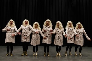 Company in blonde wigs and macintoshes